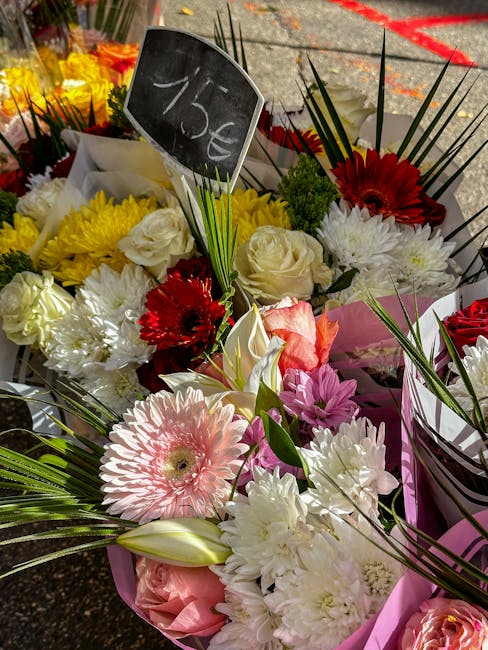 A vibrant assortment of fresh flowers displayed for flower delivery at a florist shop. The bouquet includes pink gerbera daisies, white roses, red gerbera daisies, white chrysanthemums, and pink tulip